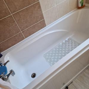 a white bath tub with a sink in a bathroom at Single Bedroom in the main Bungalow in Wednesfield