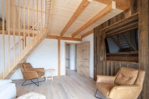 a room with two chairs and wooden ceilings at Apartment mit rundum Blick in die Berge in Faistenau
