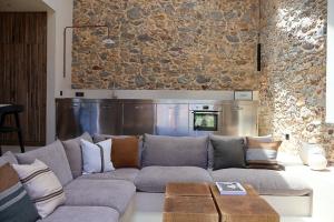 a living room with a gray couch and a stone wall at Mas Ferran Adults Only in Pals