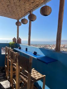 eine Bar mit Stühlen und Meerblick in der Unterkunft Blue Pearl Surf & Yoga House in Tamraght Ou Fella