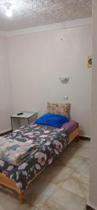 a bedroom with a bed with a blue comforter at Hostel 1er novembre khenchela in Khenchela +8 photos