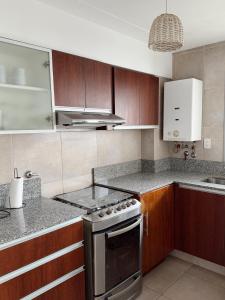 a kitchen with wooden cabinets and a stove top oven at Amplio departamento en Bv Galvez in Vuelta del Paraguayo +6 photos