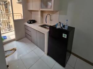 eine kleine Küche mit einer Spüle und einem schwarzen Kühlschrank in der Unterkunft Apartemen Gunung Putri by Maknyoss Rooms in Pabuaran Satu