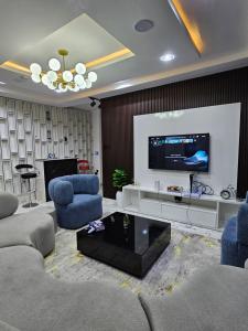 sala de estar con TV de pantalla plana y sillas azules en MOTF Apartments, en Okunola