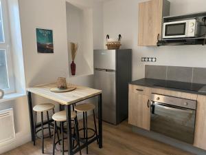 a kitchen with a small table and a refrigerator at Charmant T2 cosy à Mazamet in Mazamet