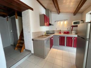 La cuisine est équipée de placards rouges et d'un réfrigérateur en acier inoxydable. dans l'établissement Gîte Grange - Village De Gîtes, à Rosières