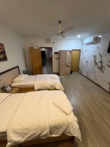 a room with three beds and a kitchen in it at Heyleez Guest House in Himmafushi