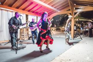 une femme en robe dansant sur une scène avec des musiciens dans l'établissement Gîte Romarin 1 - Village De Gîtes, à Rosières