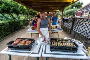 Un hombre preparando comida en una mesa en un evento al aire libre. en Gîte Olivier 1 - Village De Gîtes, en Rosières
