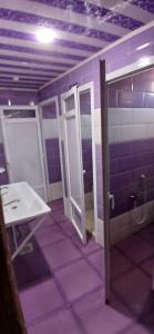 a bathroom with purple walls and a door and a sink at hostel 1er novembre khenchela in Khenchela