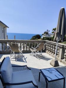 um pátio com cadeiras, um guarda-sol e uma mesa em Hotel Villa Margherita em Quercianella