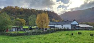 een huis in het midden van een veld met een heuvel bij Mountain Lodge, Lake View, National Park in Borrowdale Valley
