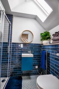 ein Badezimmer mit blauen Fliesen und einem Dachfenster in der Unterkunft Northampton 3 Bed 3 Bathroom New Duplex Apartment in Spinney Hill