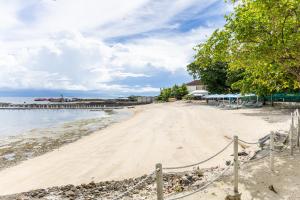 a sandy beach with a pier in the background at Dominiks Green Heaven Epic Ocean View Tambuli Pool in Lapu Lapu City