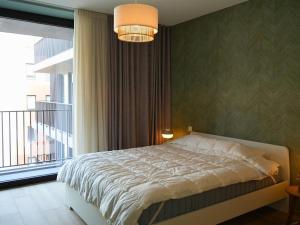 a bedroom with a bed and a large window at Appartement moderne 2 chambres & 2 parking à Koksijde by La Conciergerie in Koksijde