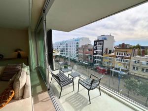 a balcony with chairs and a view of a city at Appartement moderne 2 chambres & 2 parking à Koksijde by La Conciergerie in Koksijde