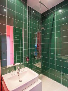 uma casa de banho com azulejos verdes, um lavatório e um chuveiro em Ibis Styles Frankfurt City em Frankfurt