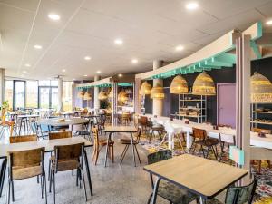 Un comedor con mesas y sillas en un restaurante. en greet Hotel Rennes Pace, en Pacé