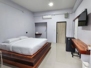 a white bedroom with a bed and a television at บ้านร่มไทร Ban Romsai Nadoem Suratthani in Ban Don Yung