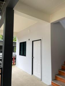 a white house with a black door and stairs at บ้านร่มไทร Ban Romsai Nadoem Suratthani in Ban Don Yung