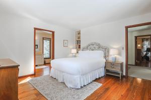 a white bedroom with a large bed and a table at RMR: Lake Creek Cottage Home in The Aspens in Wilson