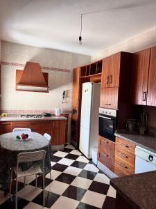 a kitchen with a table and a white refrigerator at Blue Pearl city in Chefchaouene