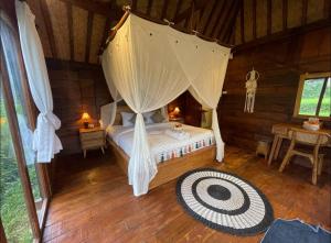 a bedroom with a canopy bed in a cabin at Umah Jati Villa in Penginyahan