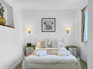 a white bedroom with a bed and two night stands at Old Coach House Ellicombe in Dunster