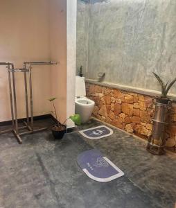 a bathroom with a toilet and a stone wall at Noah's House in Weligama