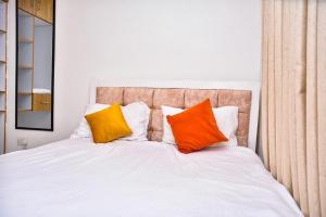 a bed with orange and yellow pillows on it at Chill Spot Meru in Kaaga