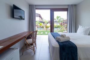 a hotel room with a bed and a desk and a window at Pousada Oasis dos Ventos - São Miguel do Gostoso in São Miguel do Gostoso
