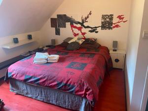 a bedroom with a bed with a red comforter at Chambres dans maison avec piscine toboggan aquatique et spa in Saint-Mars-la-Brière