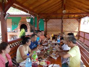 grupa ludzi siedzących przy stole jedzących jedzenie w obiekcie Casa Lucian w mieście Dubova