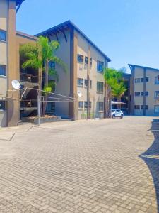 a parking lot in front of a building with palm trees at Express at Urban Cove in Nelspruit