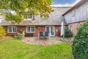 a red brick house with a patio and an umbrella at Auszeit unter Reet in Dörpum