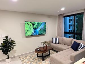 a living room with a couch and a tv on the wall at Vistas del Bosque Jacó in Jacó