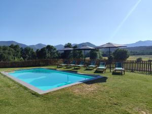 a swimming pool in a yard with chairs and umbrellas at Casa rural Ca l'Antón in Sant Miquel de Campmajor