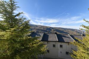 a building with a roof with mountains in the background at Chalet Copos Nevados by Surynieve in Sierra Nevada