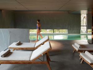 a room with three lounge chairs and a woman in the background at Domaine de la Reine Margot Paris-Issy - MGallery Collection in Issy-les-Moulineaux