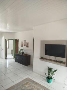 un salon avec une télévision à écran plat sur un mur dans l'établissement Ambiente Família e acolhedor, à Porto Seguro