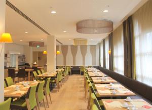 a dining room with long tables and green chairs at City-Hotel Kurfürst Balduin in Koblenz