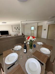 a dining table with white plates and flowers on it at Le Terrazze della Dolce Casa - Blue Wave - Casa Vacanza a Marina di Ragusa in Marina di Ragusa
