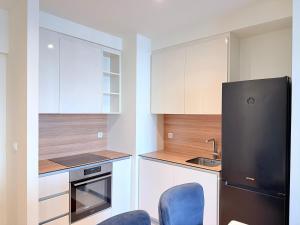 贝尔格莱德BW Arcadia RIVÉ Apartment的厨房配有白色橱柜和黑色冰箱