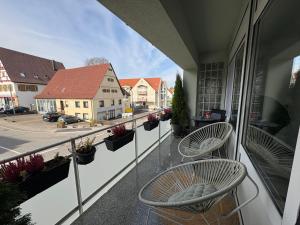 a balcony with two chairs and a view of a street at Glory's Apartment in Dußlingen
