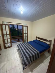 a bedroom with a bed with blue sheets and a window at Casa Azul Paraty in Paraty