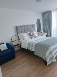 a bedroom with a large bed and a blue couch at Vive y trabaja con estilo en San Miguel, moderno departamento de 2 dorms con balcon in Lima