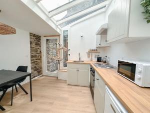 une cuisine avec des armoires blanches et une table avec un micro-ondes dans l'établissement Escapade tropicale au Costa Rica, à Profondeville