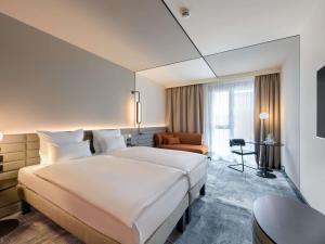 a hotel room with a large bed and a chair at Novotel Münster City in Münster +97 photos
