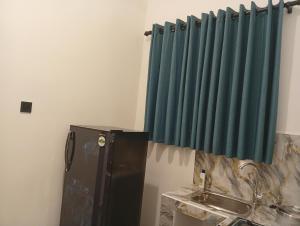 een keuken met een zwarte koelkast en een groen gordijn bij SandaLuck House Ahangama in Ahangama