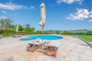 eine Terrasse mit einem Sonnenschirm und Stühlen sowie einem Pool in der Unterkunft Beautiful 4 BDR Villa With Private Pool in Hurghada